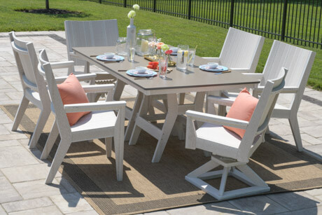 HARBOR 44” X 72” RECTANGULAR DINING TABLE IN SEASHELL WITH BRONZE HAMMERED TOP. MAYHEW CHAT DINING AND CHAT SWIVEL ROCKER DINING CHAIRS IN SEASHELL. PILLOW IN CAST CORAL.
